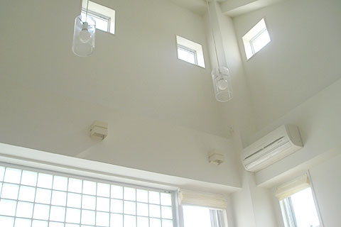 ガラスシェードの照明が吹き抜け空間に浮かぶ。昼間は存在感を隠し、夜は暖かく空間を照らす。吹き抜け空間の広がりを演出するため、あえて柱梁の形を見せ壁を凹ませた。